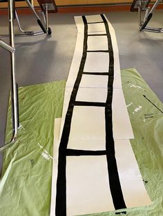 an art project is being made with black and white paper on the floor, along with chairs