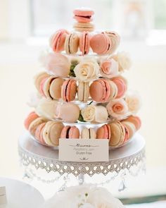 a three tiered cake with macaroons and roses on it