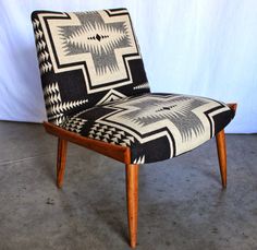 a black and white patterned chair sitting on top of a cement floor next to a wall