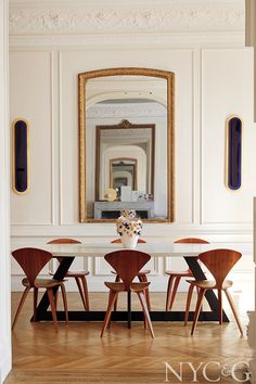 a dining room table with four chairs and a large mirror