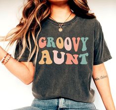 Groovy Aunt Shirt, Auntie Shirt, Family Groovy Shirts, New Aunt Gift, Hippie Floral Aunt Tee, Birthday Party Shirts, Family Matching Shirt We create custom t-shirts with great designs for everyone's liking. If you don't find the size or color you would like, please message us and we will be happy to accommodate! PRODUCT We use the finest premium Bella Canvas shirts for you, they are feather soft and very breathable with a good stretch. These t-shirts are known for their great quality and much loved by our consumers. SIZING This t-shirt comes in UNISEX sizing. It looks great on both men and women, but women are recommended to order a size down for a fitted look! Please refer the sizing chart to find your perfect fit! COLORS Colors on screen and the printed product may slightly vary due to s Multicolor Long Sleeve Tops For Birthday, Trendy Multicolor Shirt With Letter Print, Trendy Multicolor Letter Print Shirt, Retro Letter Print Tops For Gifts, Retro Letter Print Tops As Gift, Trendy Text Print Top As Gift, Trendy Birthday Tops With Funny Text, Multicolor Summer Shirt As A Gift, Cute Multicolor Tops With Funny Text