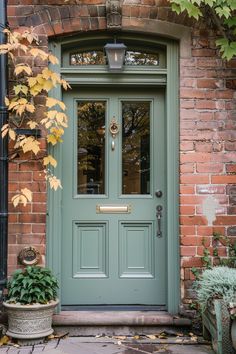 a green front door with potted plants on the side and brick building behind it