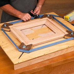 a man working on a wooden frame with wood shavings and pliers around it