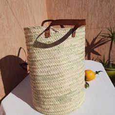 a large woven bag sitting on top of a table next to an orange and lemon