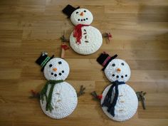 three knitted snowmen sitting on top of a wooden floor