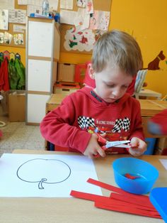 a young boy cutting out paper with scissors