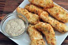 some fried food on a white plate with a small bowl of dipping sauce next to it