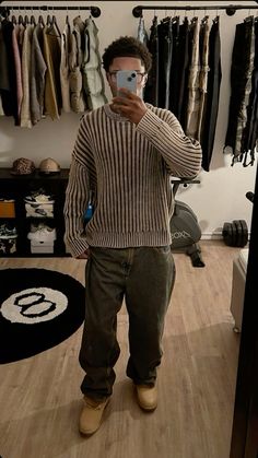 a man taking a selfie in front of his clothing rack while wearing khaki pants