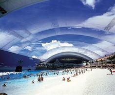 people are swimming and playing in the water under an overhanging roof at a beach