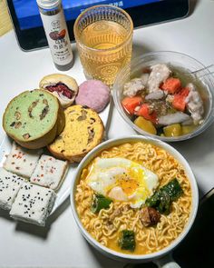 a table topped with plates of food and drinks next to a laptop computer on top of a desk