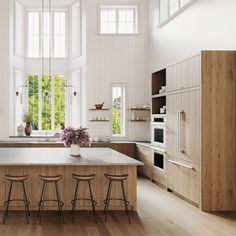 a large kitchen with wooden floors and white walls, along with an island in the middle