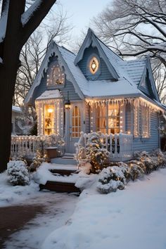 a small white house covered in snow with christmas lights on the front porch and windows