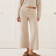 Meet The Wide Leg Sweater Pants In Oatmeal. Made Of A Merino Wool Blend, This Classic Sweater Pant Is Cropped, High-Waisted, And Has An Elastic Waist. An Added Drawstring Makes These Adjustable And An Easy Fit. Comfortable Enough To Lounge In Yet Polished Enough To Wear Out 45% Wool, 36% Viscose, 9% Nylon, 5% Cashmere, 5% Elastic Dry Clean Only Made In China Cozy Beige Bottoms For Spring, Cozy Beige Pants For Fall, Cream Pants For Loungewear In Fall, Cream Pants For Fall Loungewear, Cream Wide-leg Pants For Fall, Cozy Beige Bottoms For Fall, Cozy Cream Bottoms For Spring, Cream Loungewear Bottoms For Fall, Cream Wide Leg Winter Pants