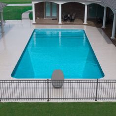 an above ground swimming pool surrounded by a white fence and green lawn with chairs around it