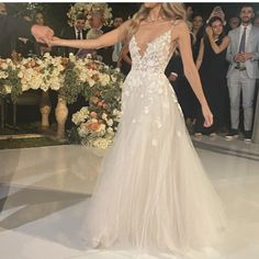 a woman in a wedding dress walking down the aisle with her hand out to someone