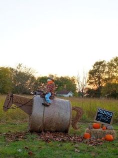 a boy riding on the back of a horse made out of hay and pumpkins