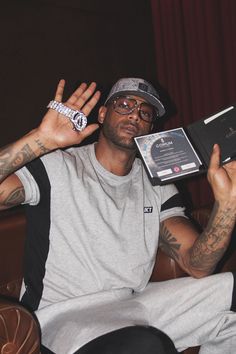 a man sitting in a chair with his hand up to the camera and holding an award