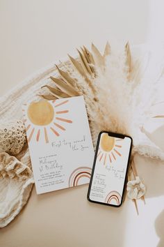 an iphone and wedding stationery sitting next to each other on a white tablecloth