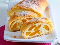 two croissants on a white plate with powdered sugar and orange slices