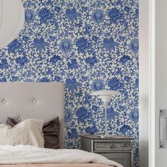 a bed sitting next to a wall with blue and white floral designs on it's walls