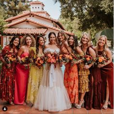 a group of women standing next to each other wearing dresses and holding bouquets in their hands