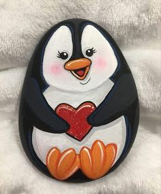 a penguin holding a heart painted on it's face