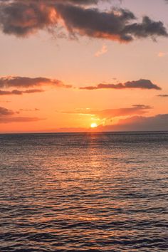 the sun is setting over the ocean with some clouds in the sky and one boat out on the water