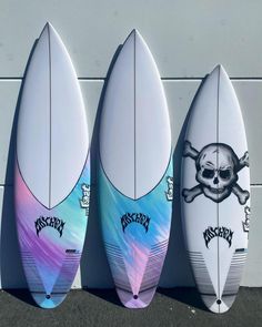 three surfboards with skulls and bones painted on them are lined up against a wall