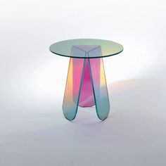 a colorful glass table with curved legs on white background in front of a light colored backdrop