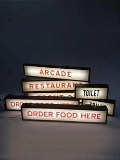 three lit up signs that are on top of each other in front of a dark background