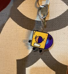 a keychain with a cartoon character on it sitting on top of a carpet