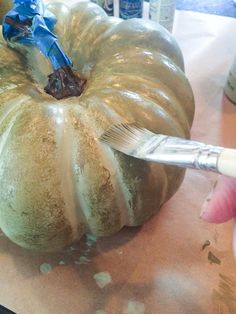 someone using a paint brush to decorate a pumpkin