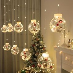 christmas decorations hanging from the ceiling in front of a fireplace