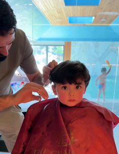 a young boy getting his hair cut by an adult