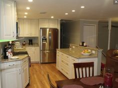 a large kitchen with white cabinets and stainless steel appliances, along with an island in the middle