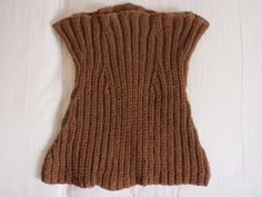 a brown knitted vest laying on top of a bed