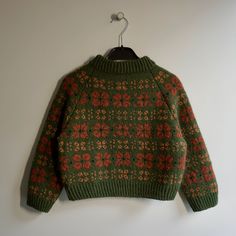 a green and red sweater hanging on a wall