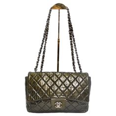 Introducing a handbag that's not just a fashion accessory but a collector's item - the Chanel 2008-2009 Metallic Patent Quilted Jumbo Single Flap in Olive Green. This stunning shoulder bag is crafted from diamond-quilted glossy patent leather, featuring leather-threaded silver-tone chain shoulder straps and a front flap with a silver-tone Chanel CC turn lock. It opens to a matte black leather interior with patch and zipper pockets. Experience Chanel's sophisticated and timeless styling in this e Designer Green Double Flap Bag, Luxury Green Double Flap Bag, Green Evening Bag With Double Flap, Green Double Flap Evening Bag, Green Chanel Bag, Chanel Jumbo Patent, Vestidos Versace, Dream Bag, Lock It