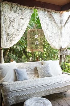 a white couch sitting under a window next to a bird cage