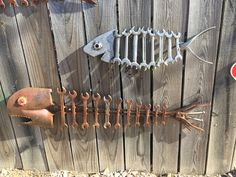 there is a metal fish and wrenches on the side of a wooden fence that has rusted parts attached to it