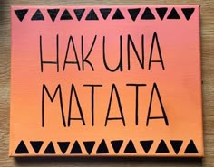 a wooden sign that says hakuna matata on it with black and pink triangles