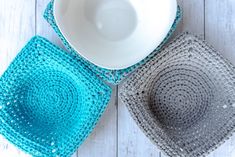 three crocheted placemats and a bowl on a white wooden table top