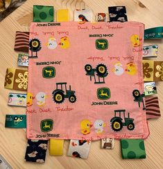 there is a pink cloth with farm animals and tractors on it, along with other fabric pieces