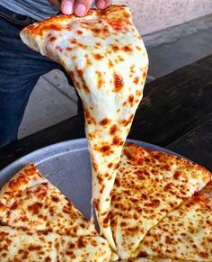 a person is taking a slice of cheese pizza