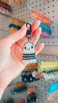 a person holding up a keychain with a small ghost on it in front of some other items