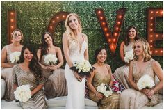 a group of women standing next to each other in front of a wall with lights