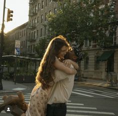 two people hugging each other while crossing the street