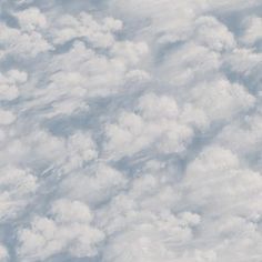 an airplane is flying high in the sky above some clouds and blue sky with white fluffy clouds