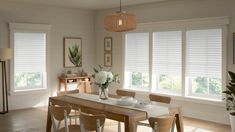 a dining room table and chairs with white flowers in vases on the table next to them