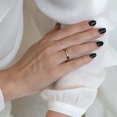 a woman's hands with black nails and a gold ring